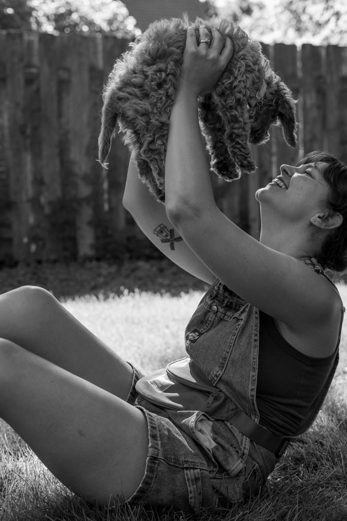 Atlas a cockapoo puppy being held up my a woman smiling back at her